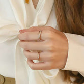 Model clasping hands, showing matching two-tone gold twisted bands against ivory blouse